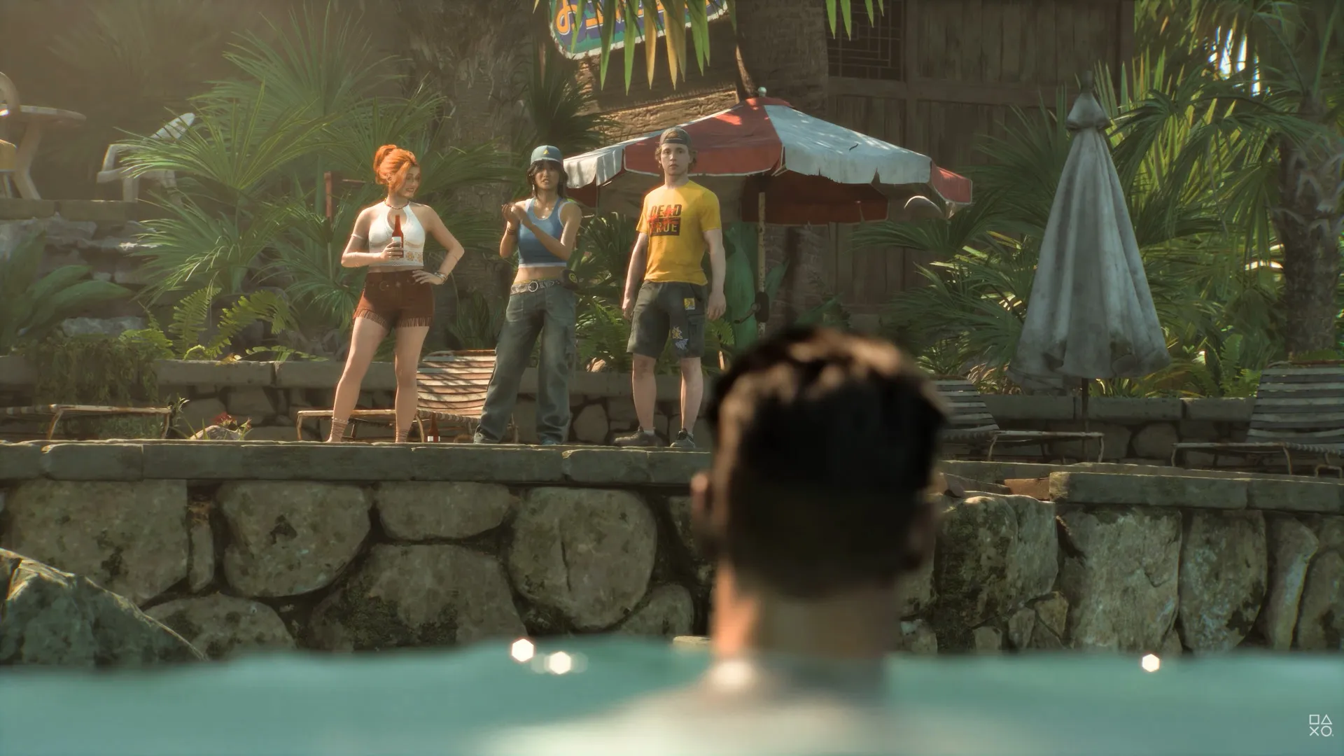 Grupo de adolescentes observa um personagem na água em um resort cercado por vegetação tropical durante uma cena de Until Dawn
